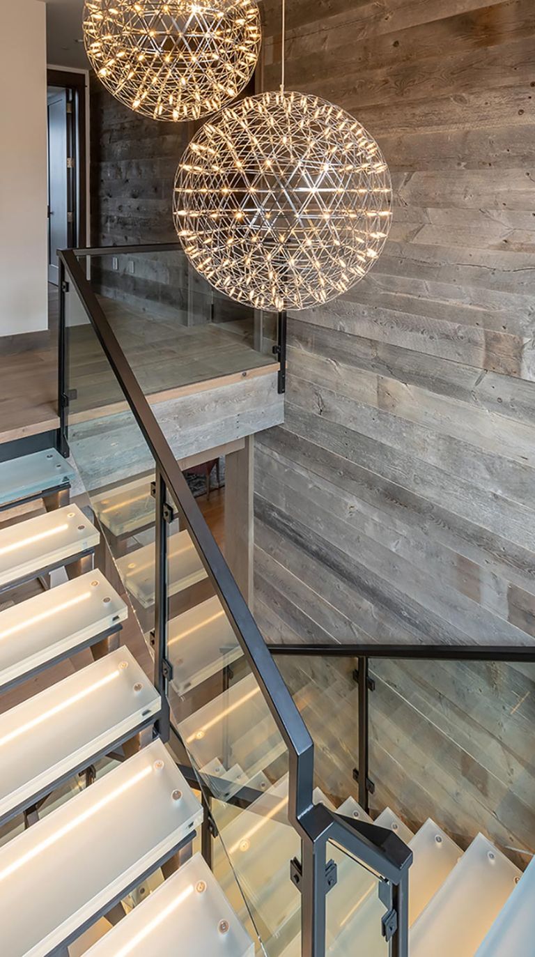 Glass staircase with illuminated steps and large spherical pendant lights