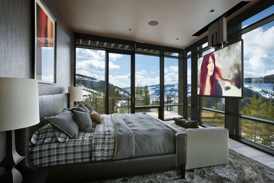 A bedroom overlooking the mountains with in-ceiling speakers and a TV display descended from the ceiling.