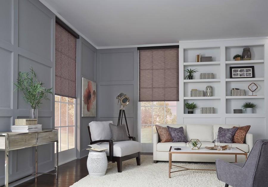 a living room with white sofas and motorized shades.