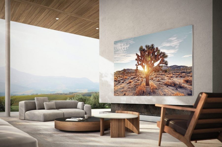 A Samsung TV is hung on an outdoor patio wall with a mountain view in the distance.