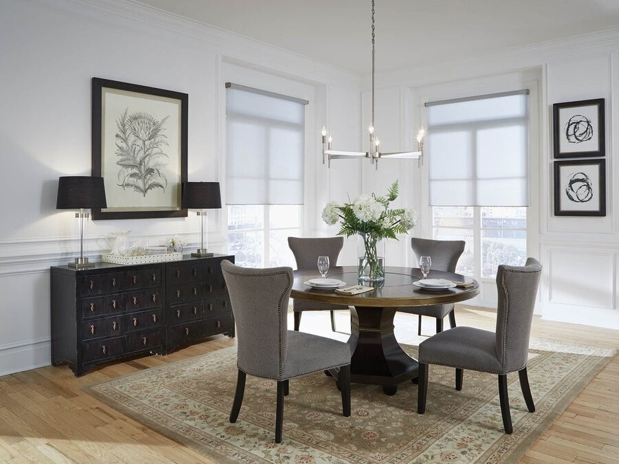 A dining table setup featuring Lutron lighting fixtures and motorized shades in the room