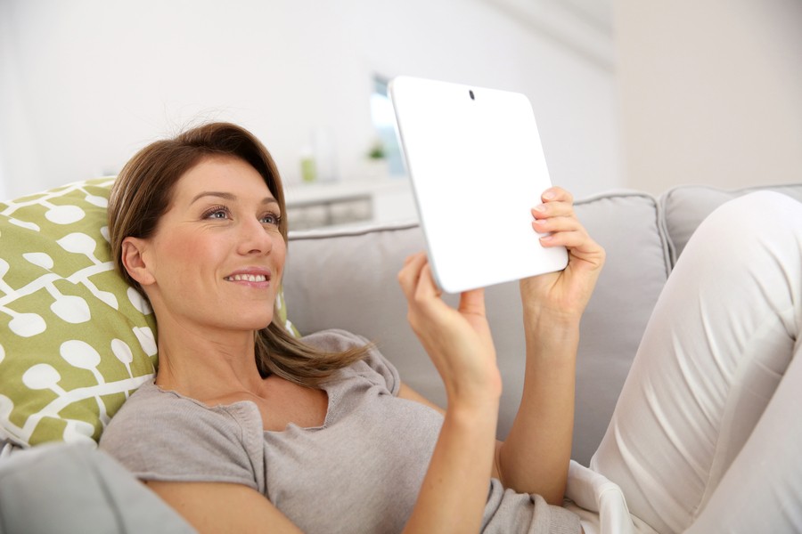 A woman enjoys the fast connectivity on her tablet from her home network setup.
