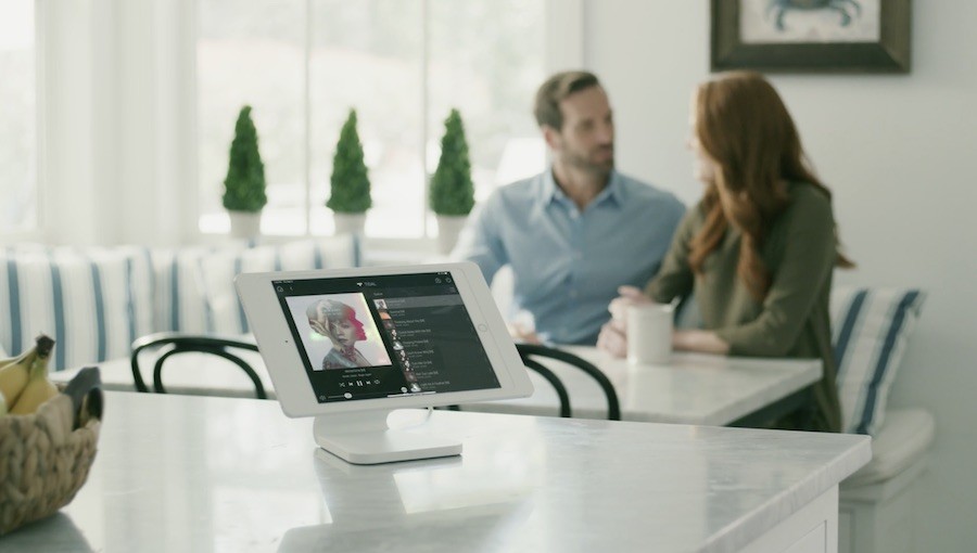 Control4 ipad interface on a kitchen counter with two people sitting in the background