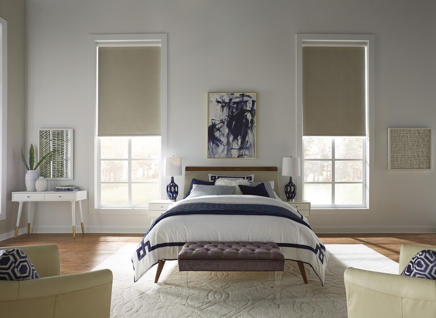 A bedroom featuring minimalist decor and plush textures, complemented by understated window shades that invite natural light in. 