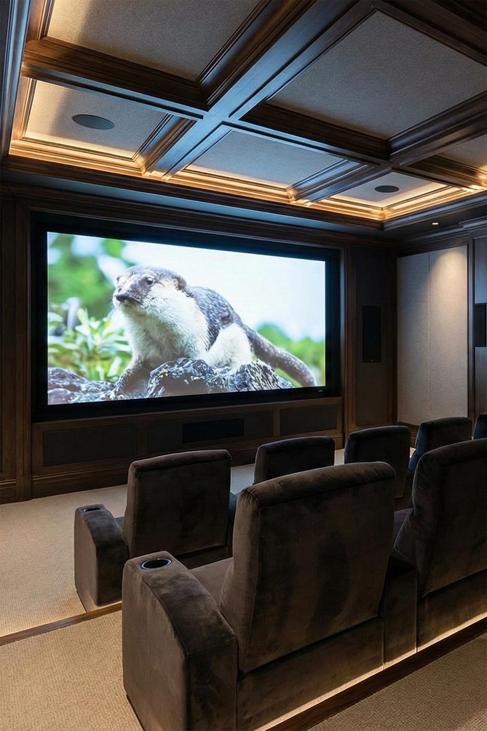 Elegant home cinema with a coffered wood ceiling and rows of velvet theater chairs
