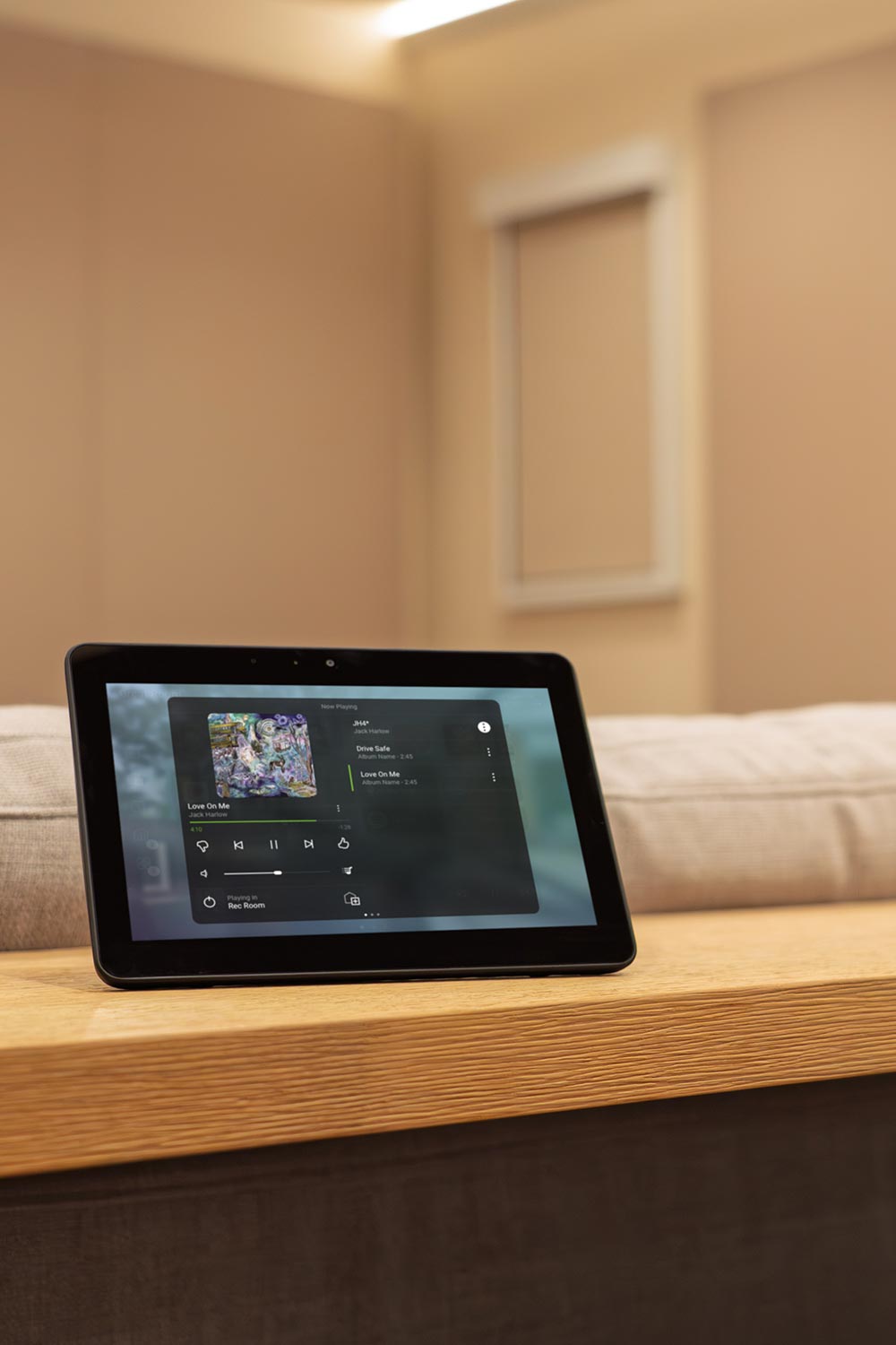 Digital tablet displaying a music streaming interface resting on a wooden armrest