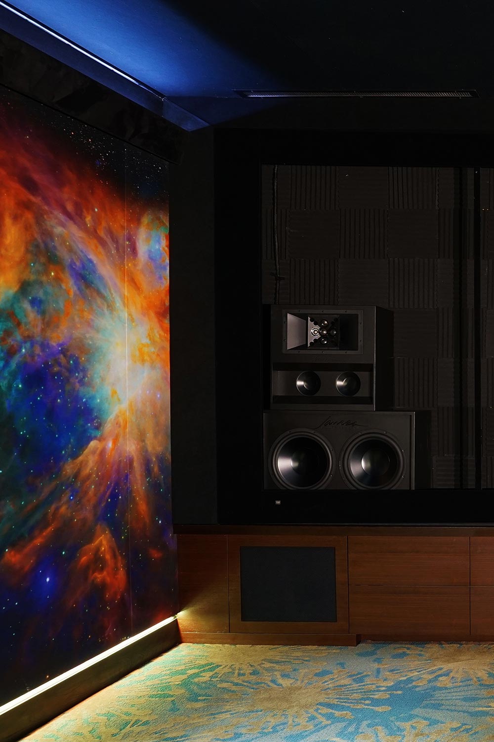 Professional wall-mounted subwoofer and speakers installed next to a colorful space mural
