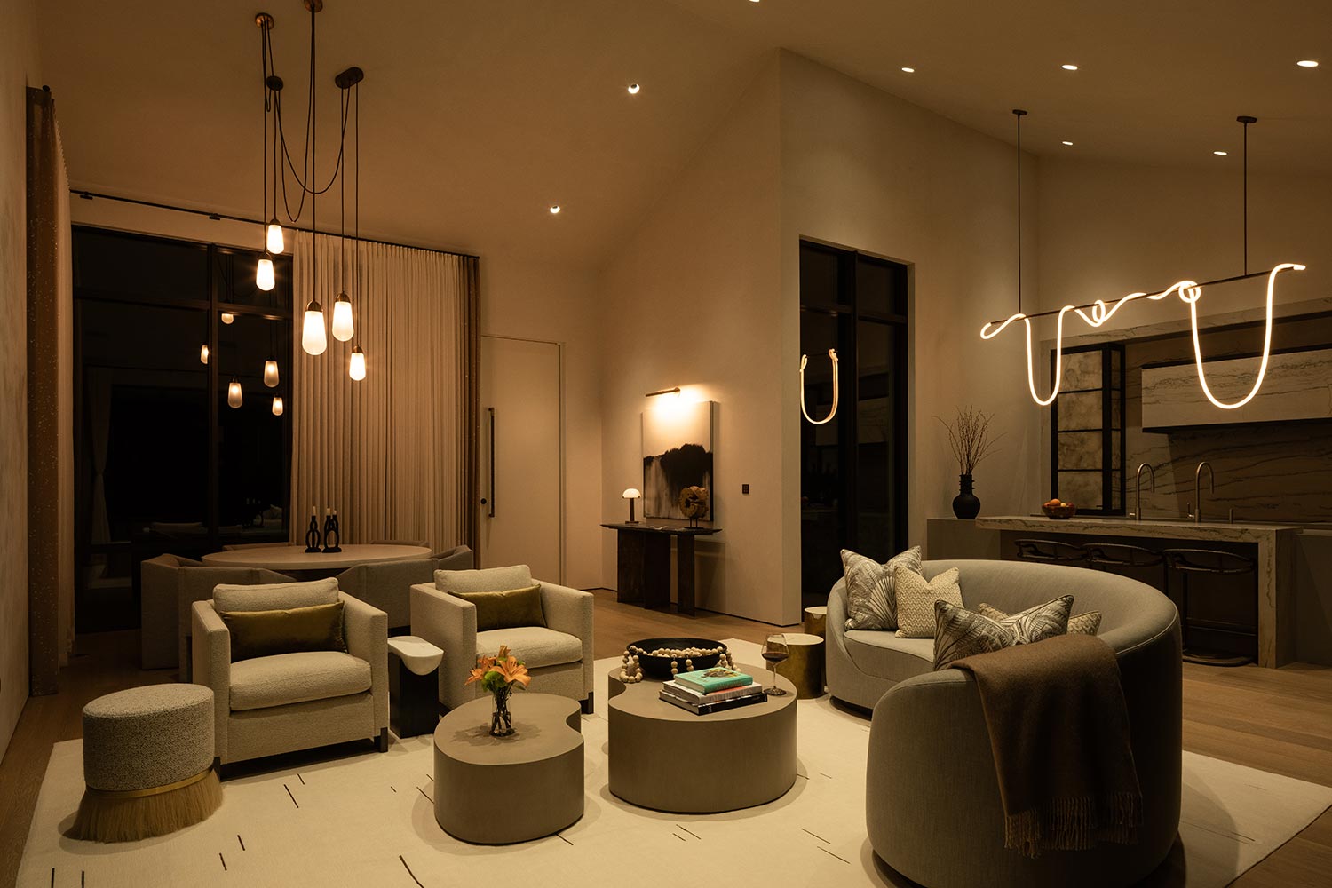 Modern open floor plan living room and kitchen at night with dim, warm ambient lighting