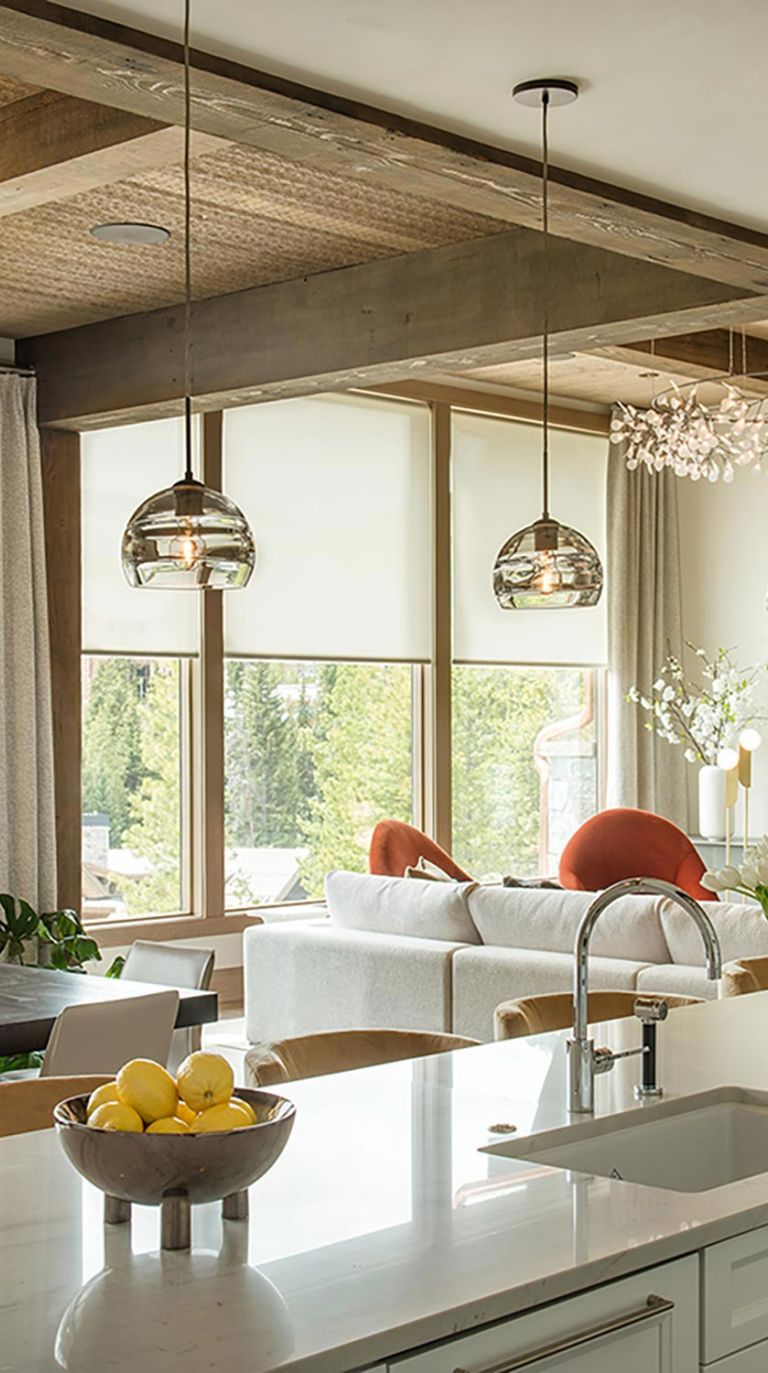 Modern kitchen view of living room with motorized roller shades and pendant lights